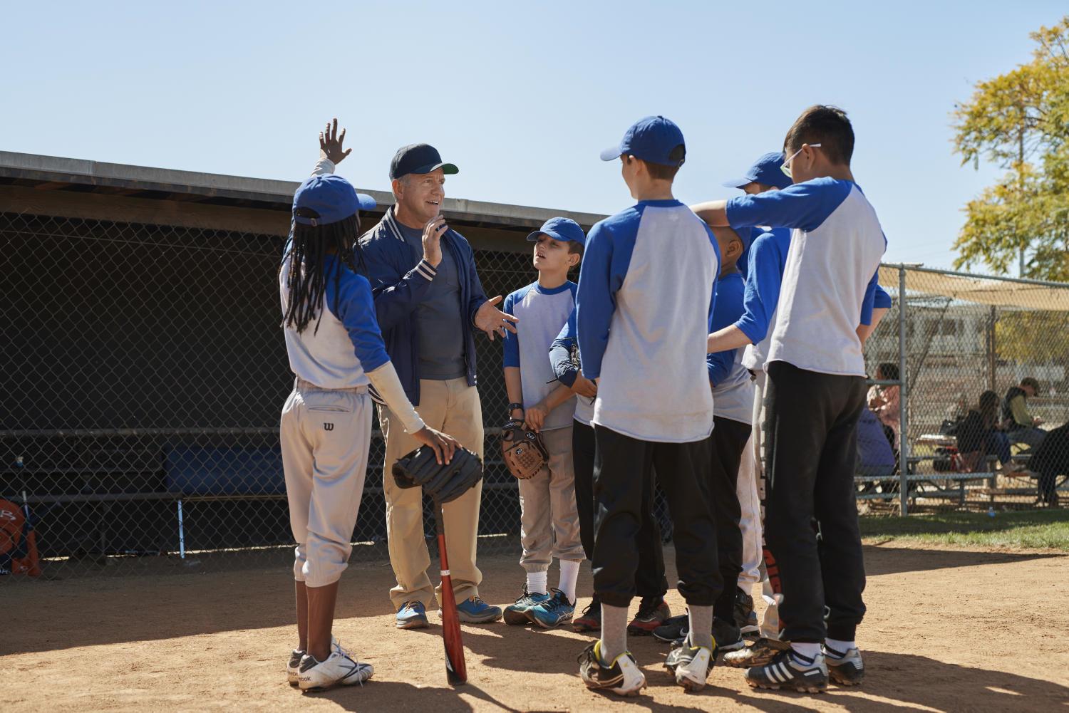 Happy Coach talks to baseball players wearing Beltone Amaze hearing aids.