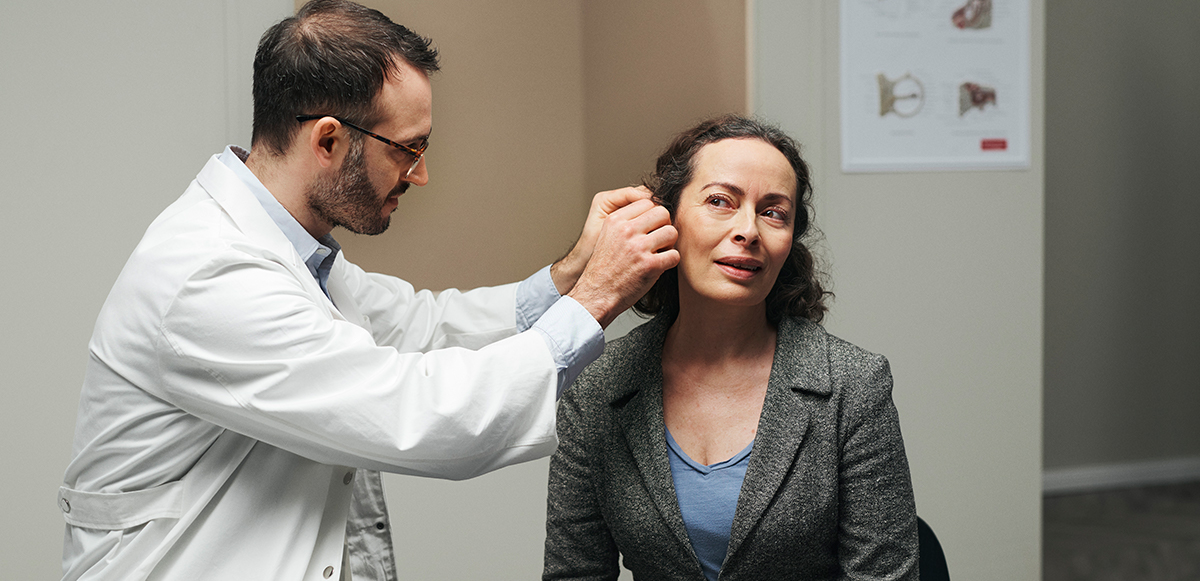Audiologist fitting a ReSound hearing aids user.